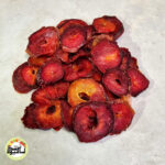 اسلایس‌های حلقه‌ای آلو خاکی خشک با رنگ قرمز تیره و بافت گوشتی که روی سطحی روشن قرار گرفته‌اند.