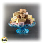 تکه‌های مکعبی و رنگارنگ بستنی خشک انجمادی در طعم‌های مختلف که در یک ظرف پذیرایی آبی رنگ زیبا چیده شده‌اند.