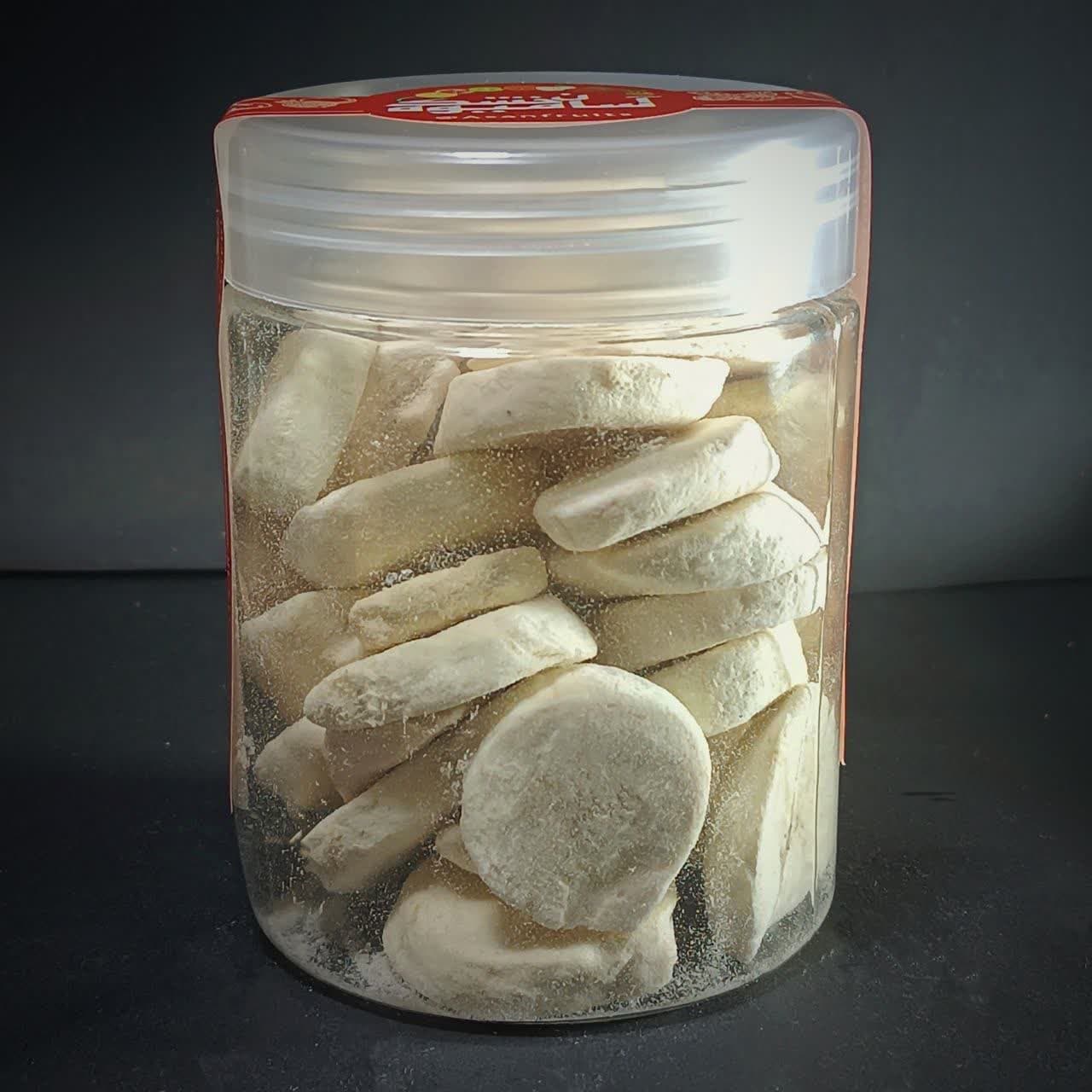 اسلایس‌های موز خشک انجمادی با رنگ روشن و بافت پفکی در یک ظرف شیشه‌ای شفاف.